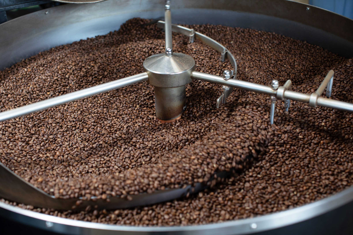 Coffee beans being roasted in a large industrial roaster.