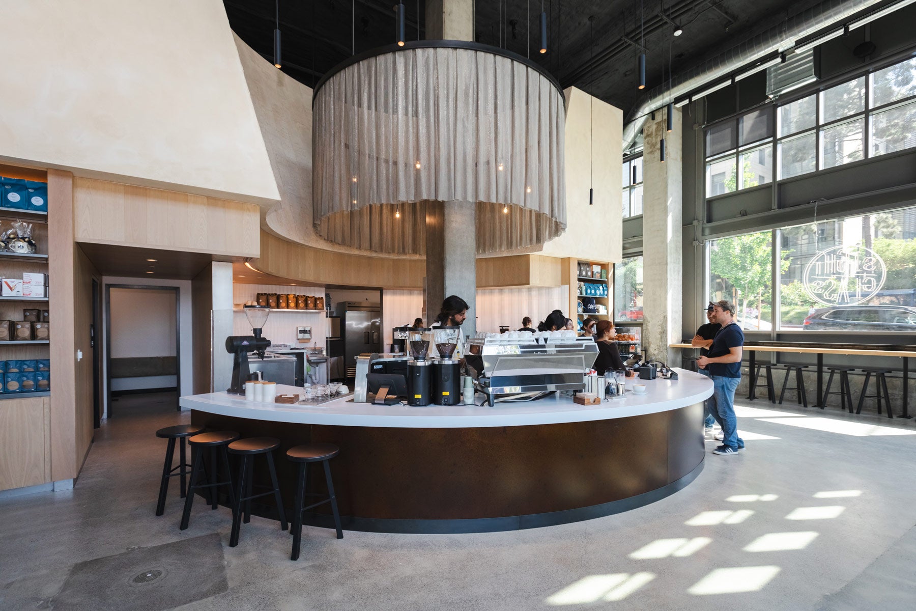 Modern coffee shop interior with a curved counter and bar stools.