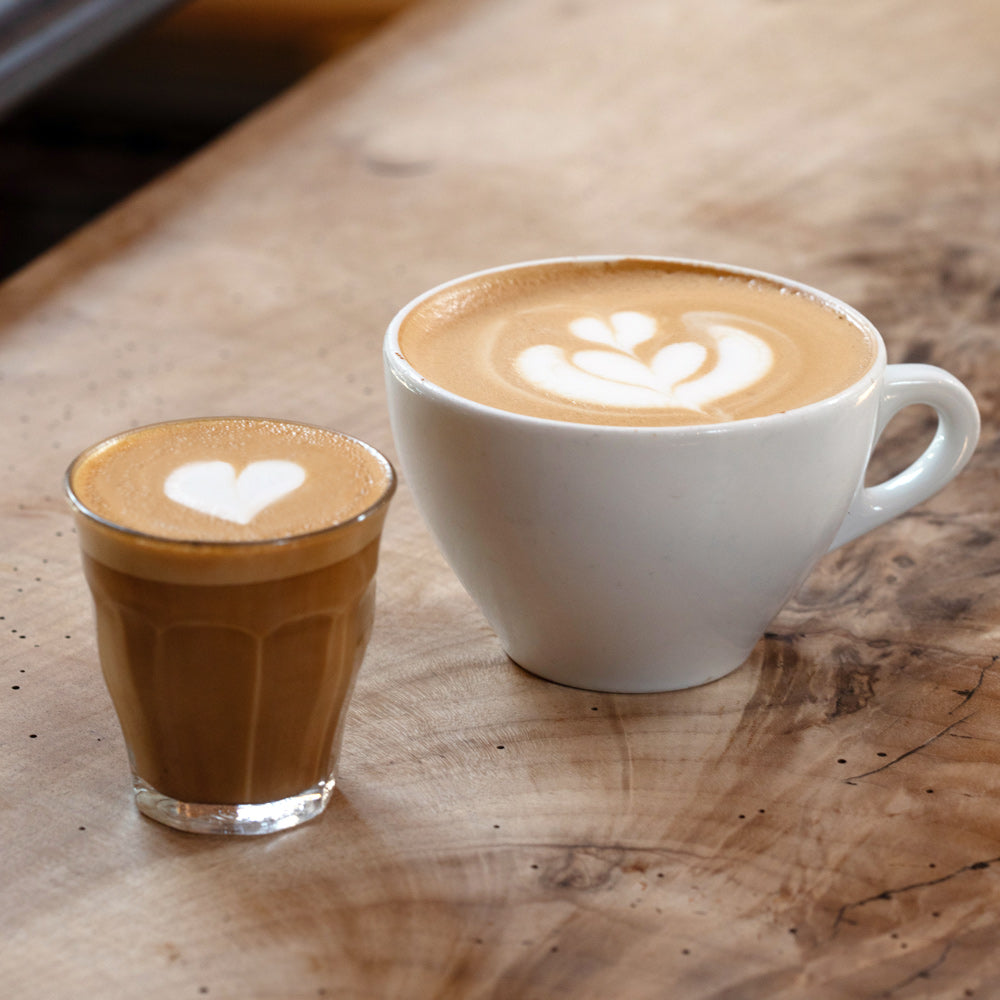 Two cups of coffee with latte art on a wooden surface