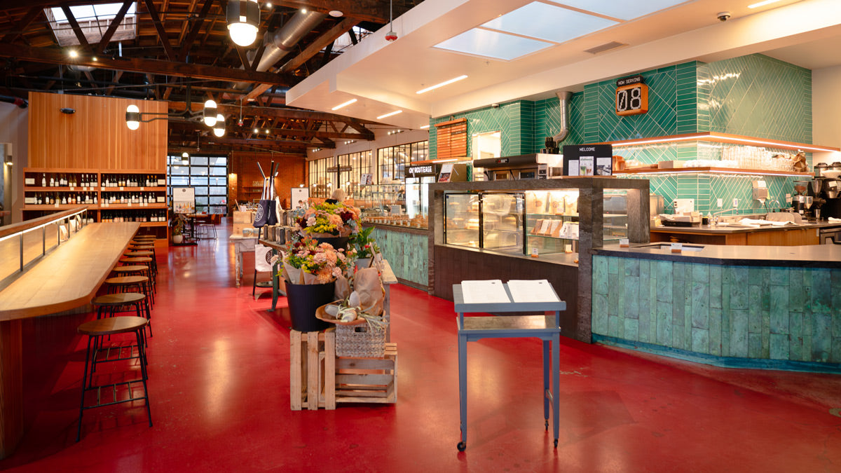 Modern bakery interior with red floor, green walls, and various display cases.
