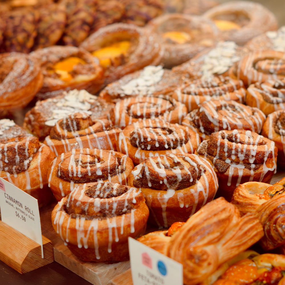Display of cinnamon rolls with various toppings at a bakery.